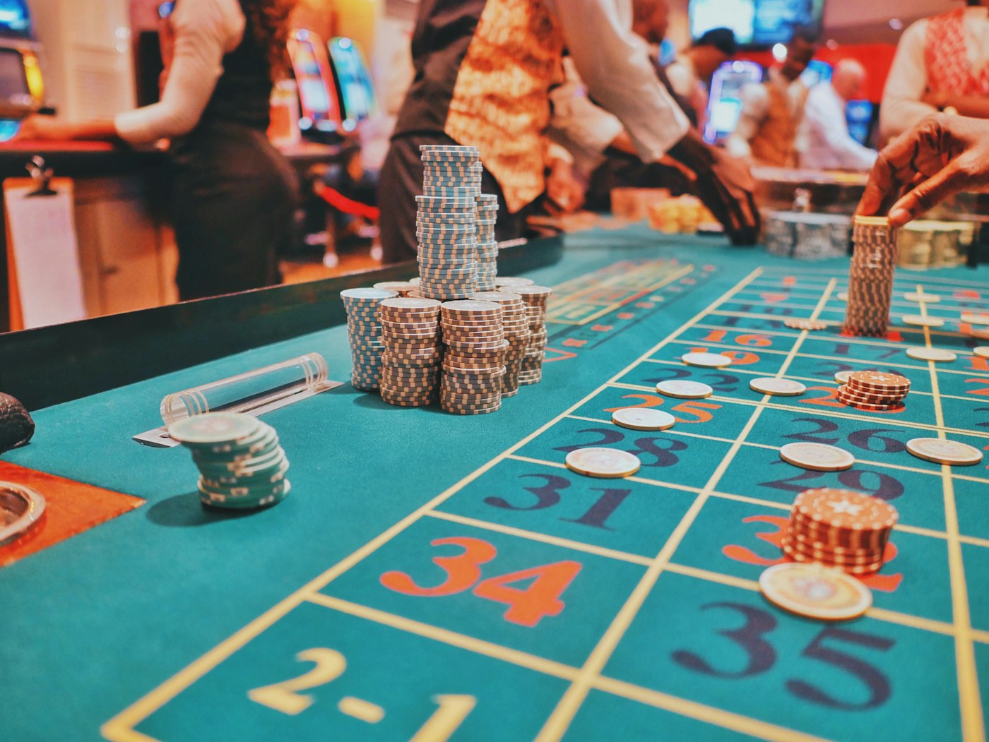 Elegant casino gaming tables with green felt and warm chandelier lighting
