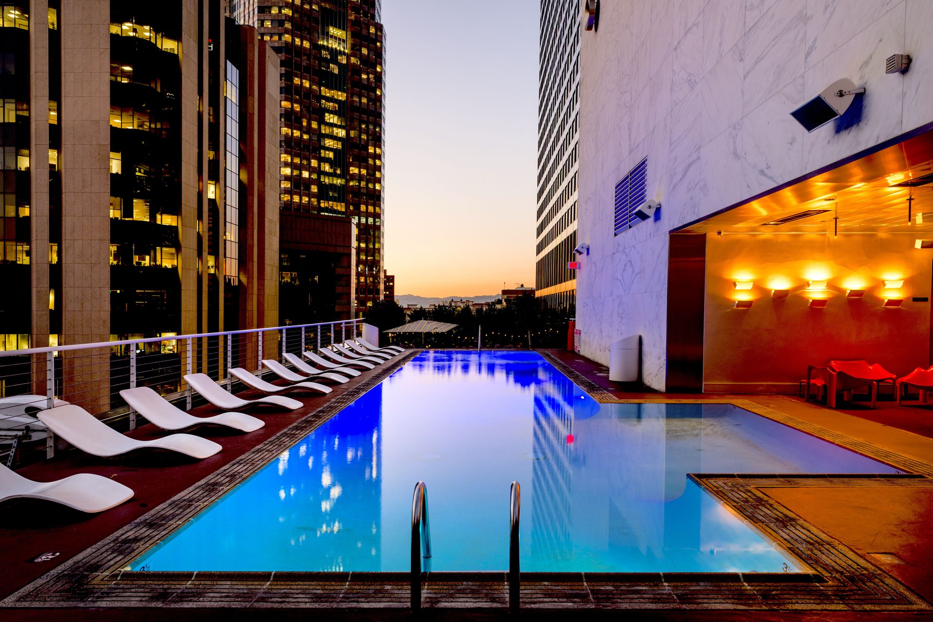 Rooftop infinity pool terrace with lounge chairs overlooking the city